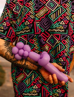 a balloon shaped like a flower behind the back of someone with a very colorful shirt