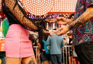 a couple in colorful clothes hold hands in the crowd at the carnival