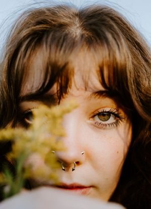 a woman's face is half covered by yellow flowers