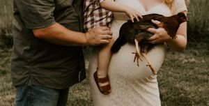 a mom and dad hold their toddler and a chicken in Western North Carolina just outside of Asheville