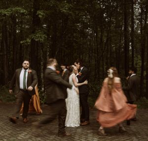 a bride and groom share a kiss in a circle of their peers parading around them