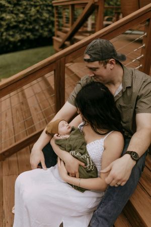 a mother, father, and infant sit together on the wooden steps
