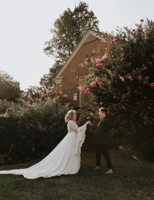 a couple exchanges flowers in front of a brick building in Western North Carolina near Asheville