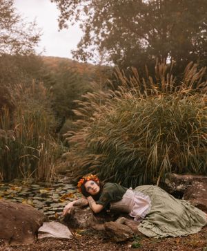 a girl dressed as a hobbit lays out on the rocks in Western North Carolina near Asheville