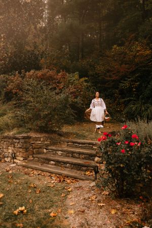 a lady in a dress is about to walkdown the steps by the rose bushes out in nature in Western North Carolina near Asheville and Boone