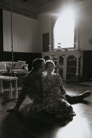 a monochrome shot of a couple sitting in the floor in front of a window with light pouring in