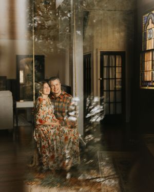 a couple sit inside smiling with the reflection of outside cast onto them