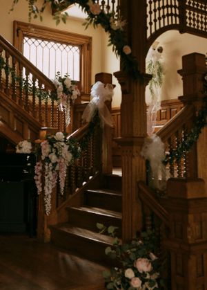 a stairway is draped in flowers and greenery awaiting the bride