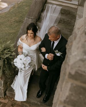 a father walks his daughter down the stone steps to the alter to be wed