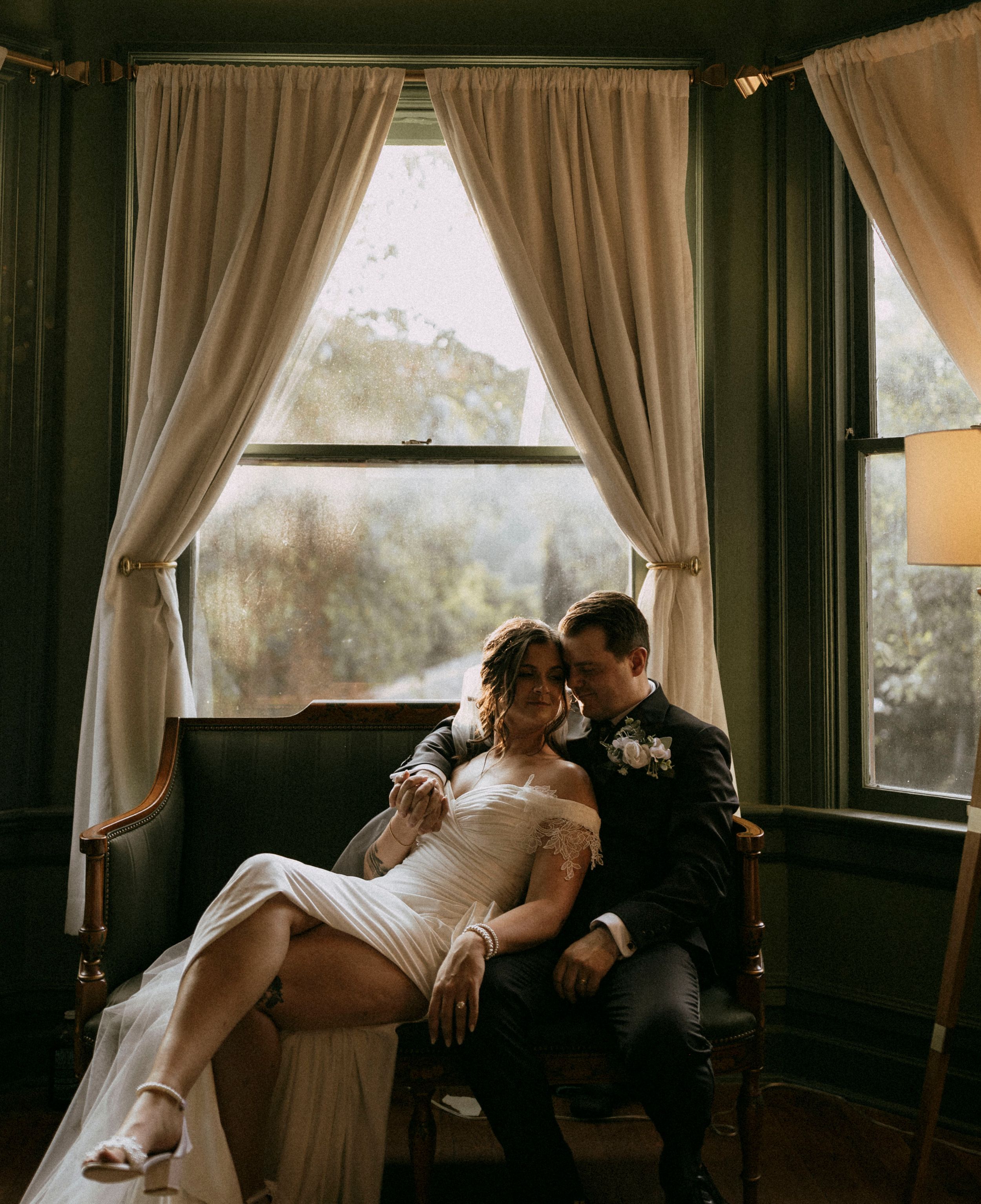 a bride and groom sit on a green couch