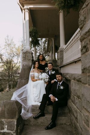 a wedding party sits stoically on the stone steps