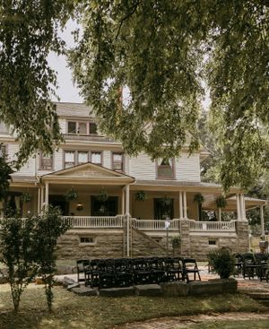 trees line the top of this scene while the black chairs sit empty awaiting wedding guests