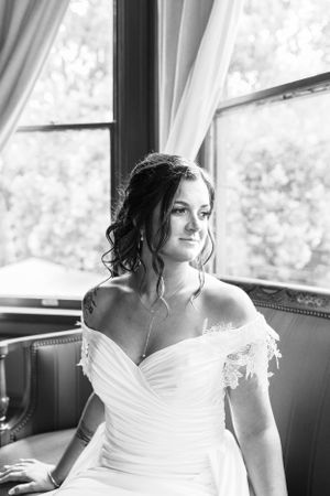 a bride in black and white looks out the window awaiting her guests