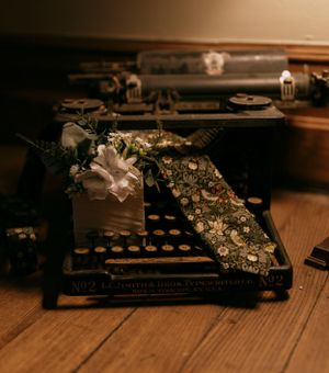 a vintage typewriter holds a floral tie and flowers