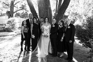 a large family group gather in front of a tree for a photo at a wedding