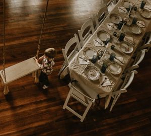 a boy pushes a swing inside beside a table set for a nice dinner