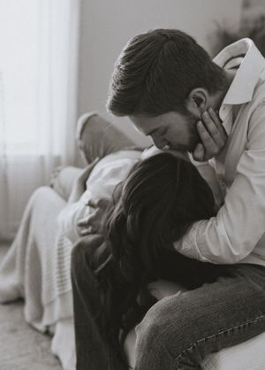 a man leans down to kiss the head of the woman who is laying in his lap shown in black and white