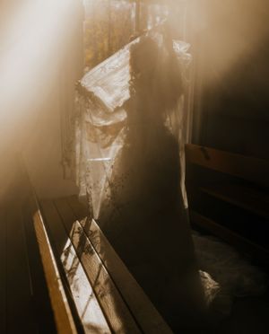 a woman holds her dress up in the light of the window of a small chapel in Western North Carolina near Asheville and Boone