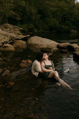 a couple sit in the water and share a kiss amidst the rocks and trees