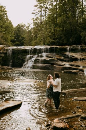 a couple embrace in the water by a waterfall in western North Carolina in Asheville
