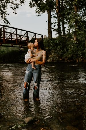 a mother lovingly kisses her child while standing in the creek in Western North Carolina just outside of Waynesville