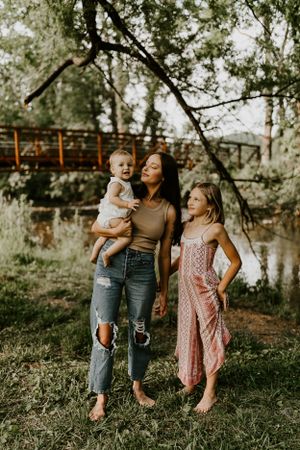 a mother and her two children stop under a tree near the creek in Western North Carolina just outside of Asheville and Waynesville