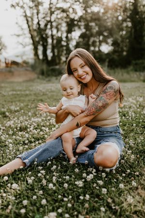 a mother lovingly leans against the face of a toddler in a field of clovers in Western North Carolina near of Asheville and Waynesville