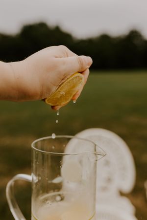 a hand squeezes a yellow lemon into a glass