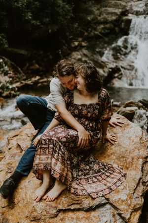 a couple is hugging in front of a waterfall in Western North Carolina just outside of Asheville