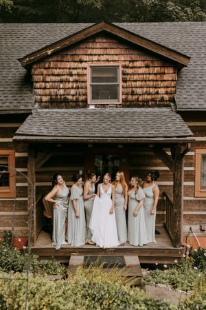 a bride and her bridesmaids gather on the porch of a tiny cabin