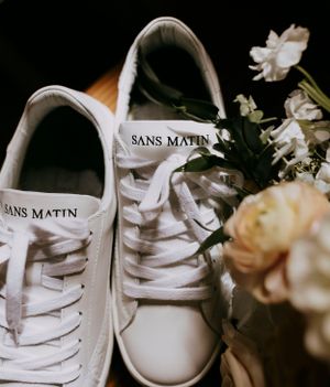 a brides white shoes that say sans martin sitting by her bouquet