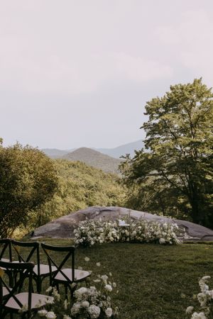 a empty ceremony site adorned with white flowers and the Blueridge mountains in the background