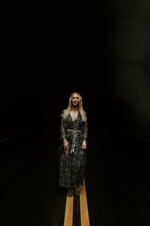 a woman stands alone in the darkness emerging to the light from a tunnel in Western North Carolina just outside of Asheville