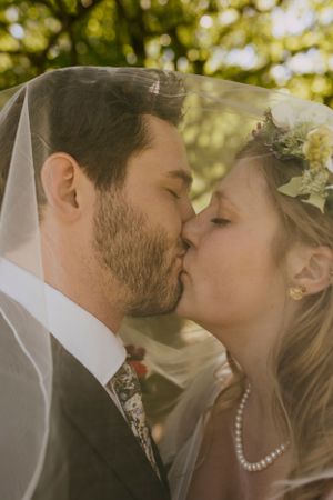 a man and woman share a kiss under a veil on their wedding day