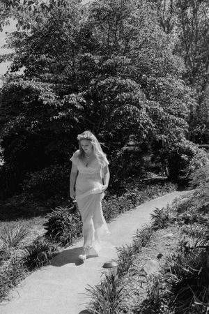 a black and white shot of a bride walking through the garden