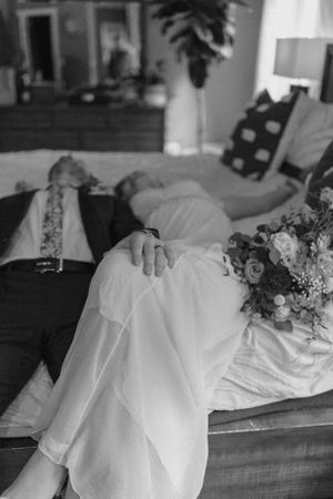 a bride and groom fall back on the bed to decompress after their wedding ceremony