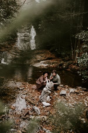couple petting their dog beneath a waterfall in western north carolina