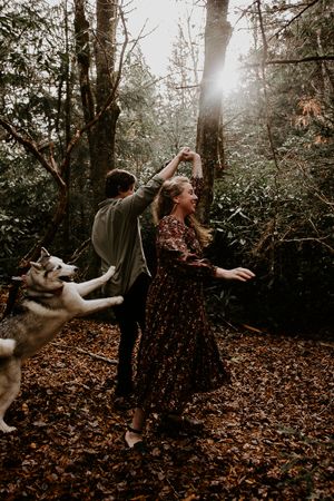 a couple spinning in the forest as their dog plays along outside of asheville in western north carolina