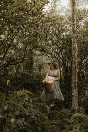a woman carries a basket of laundry through the woods in Western North Carolina near Asheville