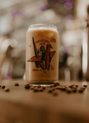 a large cup of iced coffee sits on a wooden block surrounded by coffee beans in Western North Carolina just outside of Asheville