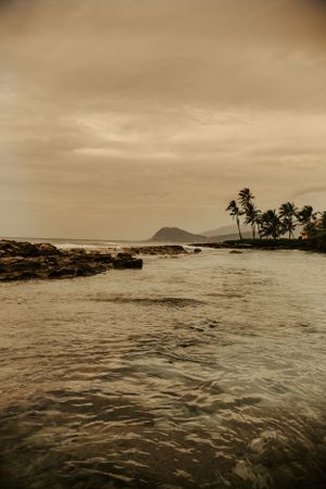a gloomy day in Hawaii overlooking the ocean with a small mountain in the background