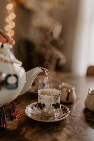 a vintage glass tea kettle pours a steaming cup of tea in Western North Carolina just outside of Asheville
