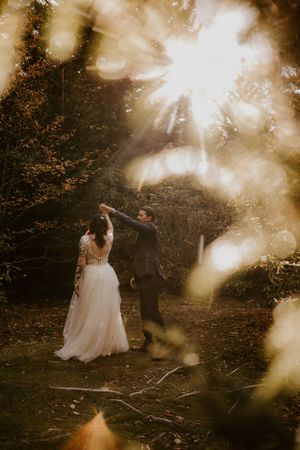 a couple in the dance in the woods amid the golden light bouncing off the evergreens in Western North Carolina just outside of Asheville