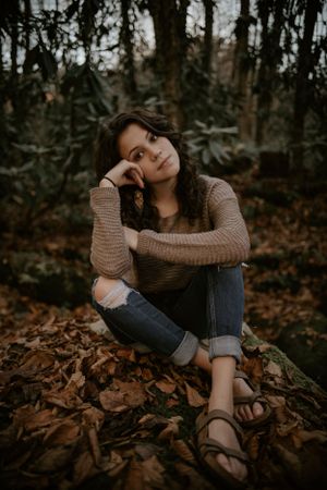 a young woman sits in the woods and ponders in Western North Carolina just outside of Asheville