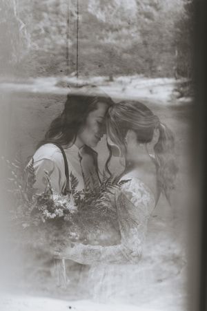 two brides sharing a moment to embrace with a reflection of the river behind them in Western North Carolina just outside of Asheville