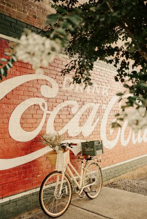 a vintage bike with baskets is leaned against a brick wall with a large Coca-Cola mural in Western North Carolina near Asheville
