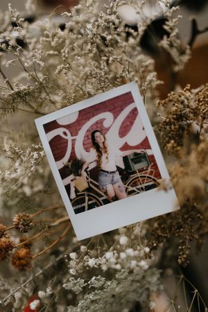 a polaroid photo on a bouquet of flowers the photo contains a woman posing with her vintage bicycle in front of a Coca-Cola mural