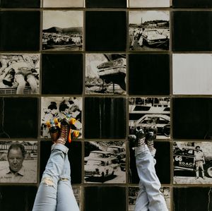 two people wearing roller-skates have their feet propped up on a checkered mural