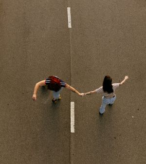 an ariel view of two girls roller skating together while holding hands on the road