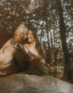 a couple smiling at each other with the reflection of trees
